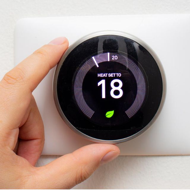 A photo showing Nest thermostat being set by a woman's hand